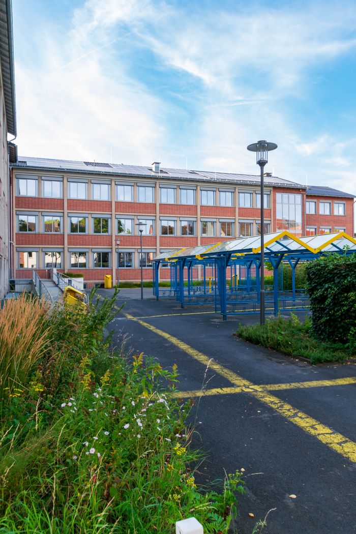 A contemporary school building with colorful playground structures on a sunny day.